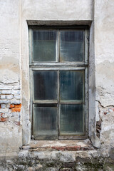 Old dirty dilapidated wooden window in a crumbling brick building. The building urgently needs a major overhaul.