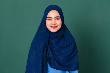 portrait of young happy smiling confident beautiful Muslim woman dressed nicely wearing blue hijab...