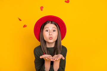 Photo portrait of lovely girl sending air kiss with flying in air red heart isolated bright yellow...