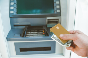 Close-up, A man holds in his hand a bank card with money. Against the background of an ATM.