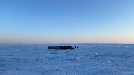 A large long winter tent with a stove stands on the ice of the frozen snow-covered Lake Baikal. B