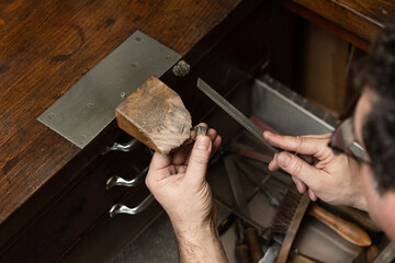 goldsmith sands a silver ring on the workbench.