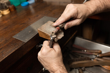 goldsmith sands a silver ring on the workbench.