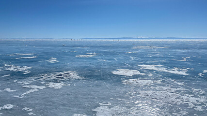 Fototapeta premium Panorama of the winter lake Baikal. People are skating. Beautiful winter landscape