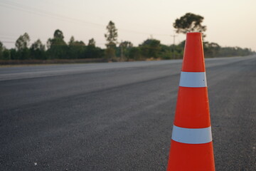 Red rubber cones are placed in the paved road.