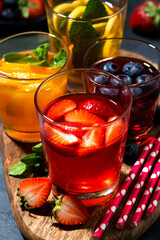 fruit and berry beverages in assortment on dark background, top view closeup