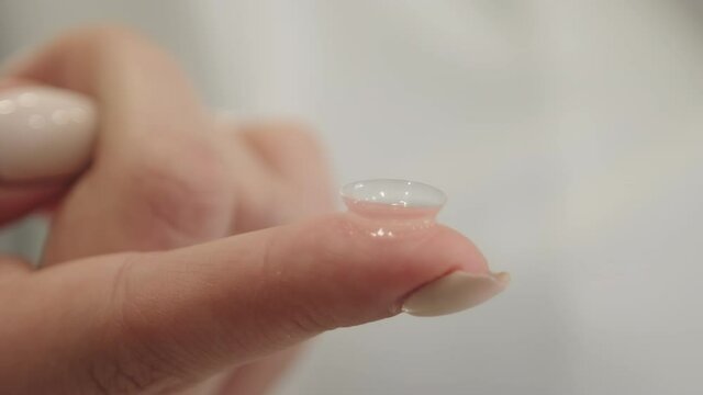 Panning closeup of contact lens on female ophthalmologist finger