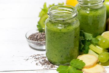 healthy green fruit and vegetable smoothies in jars on white table