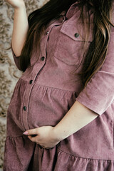 A pregnant girl is holding a tummy. The happiness of motherhood. Young beautiful girl at home.