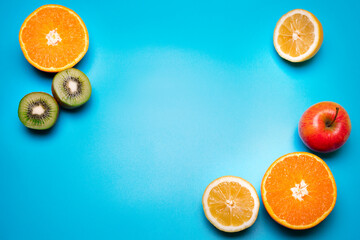 Fruits on the blue background. Orange, lemon, kiwi, apple. Free space for text.