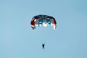 Parasailing people against a blue sky on black sea. Sunny summer day. Back view. Crimea, Sudak - 10 October 2020.