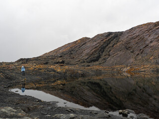 Moody landscape of mountains and lagoon with person looking at reflection in Nevado Pastoruri, Huaraz, Peru	