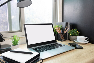 Laptop computer with white blank screen on desk in workspace and copy space concept