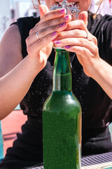 Woman opening a bottle of cider on a terrace on a sunny day