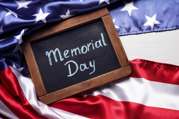 Chalkboard with text MEMORIAL DAY and USA flag on table