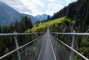 high suspension bridge between mountains trees and rocks