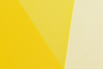 Layout of triangles papers in three different shades of yellow. Light and dark yellow background. Wallpaper in spring colors. Backdrop for writings.