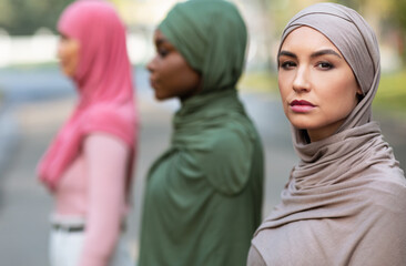 Side-View Group Portrait Of Three Diverse Muslim Women Posing Outside