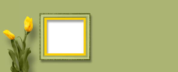 Beautiful yellow tulips with green foliage in vintage wooden frame on bright green wall for...