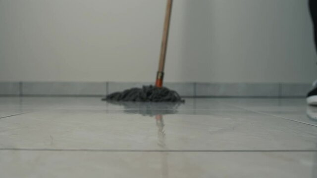Close-up frame of a mop moving on the floor on a tile. Cleaning and cleanliness