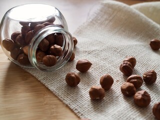 Hazelnuts in a glass jar on wooden background. Copy space