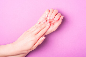 Beautiful female hands showing fresh cute manicure, skin and nail care concept, purple background