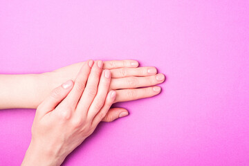 Beautiful female hands showing fresh cute manicure, skin and nail care concept, purple background