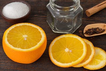 Ingredients for making an orange jam on a dark wooden table. 