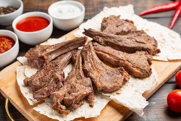 Roasted lamb ribs with sauce on wooden background,