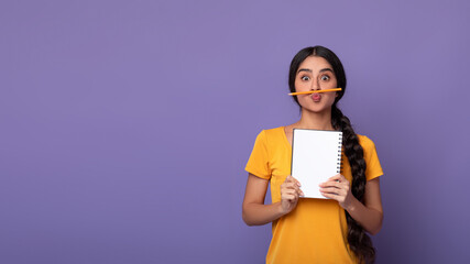 Funny indian lady holding pen as moustache over purple background