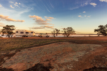 Landscape view of a a large white caravan and modern 4WD vehicle at a free camp next to the nearly dry salt Lake Norring near Wagin in Western Australia in late afternoon sunshine. - obrazy, fototapety, plakaty