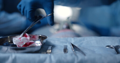 Close-up of nurse taking medical instruments for operation with colleagues performing in background