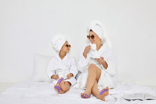 happy woman and her daughter in white bathrobes