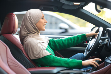 Happy muslim woman test driving new car in urban city