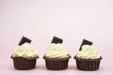  Set  cupcakes with vanilla cream decorated with  pink beads  and chocolate on pink background with  copy space for text .