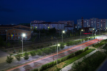 Tole bi street in the city of Uralsk, Kazakhstan. Night street lighting. Safe street at night. Illumination of roads and sidewalks at night. Long exposure red car trail