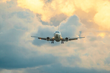 A passenger jet airliner is landing at sunset