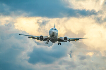 A passenger jet airliner is landing at sunset