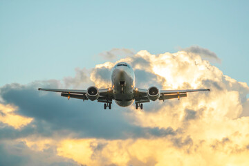 A passenger jet airliner is landing at sunset