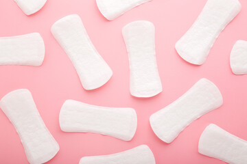 Many new white panty liners on light pink table. Pattern background. Pastel color. Closeup. Female...