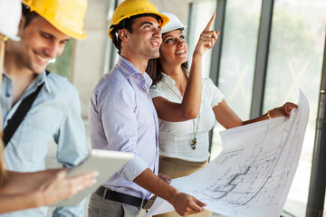 Two architects and engineers looking and discuss with about blueprint and construction project.