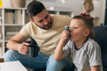 boy using asthma pump at home - obrazy, fototapety, plakaty