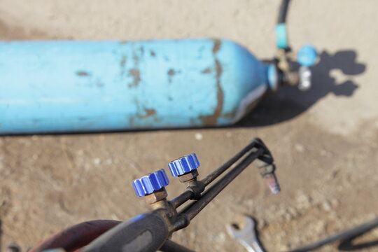 Oxygen-propane gas burner torch closeup on blue oxygen cylinder background, oxygen-propane metal gas cutting