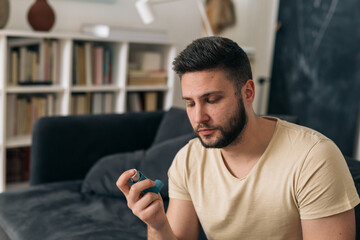 man using asthma pump at home