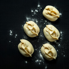 manti semi-finished products on the background of meat in the dough