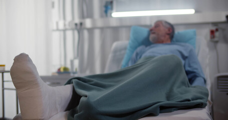 Senior male patient with broken leg lying in hospital bed