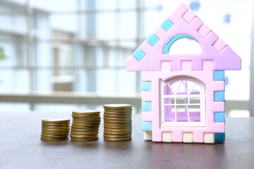 the concept of house finance with stack of coins and a house on table 
