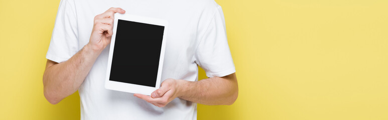 partial view of man showing digital tablet with blank screen on yellow, banner
