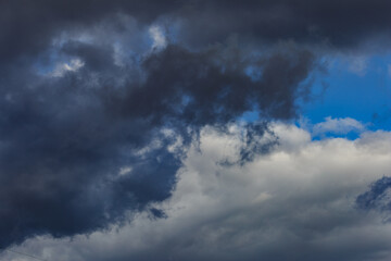 Naklejka na ściany i meble Dark storm clouds on a bright blue sky. Sky patterns background 2021.