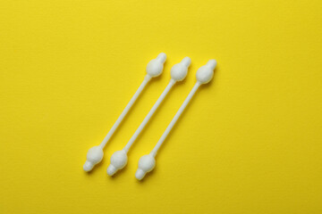 Cotton swabs on yellow background, close up